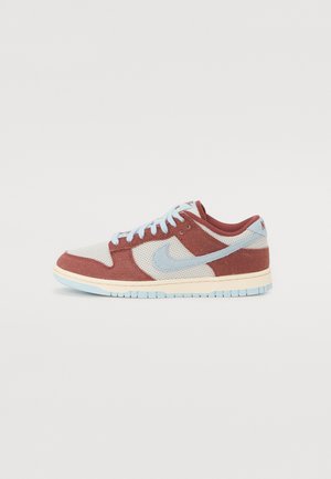 Baskets basses avec panneaux bordeaux et bleu clair, texture en mesh, lacets bleu clair et un swoosh Nike bleu clair sur le côté.