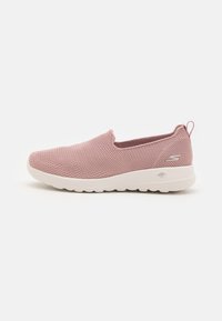 Zapatilla rosa de malla sin cordones con suela blanca, que presenta una parte superior texturizada y una pequeña lengüeta en la parte posterior para facilitar el calzado.
