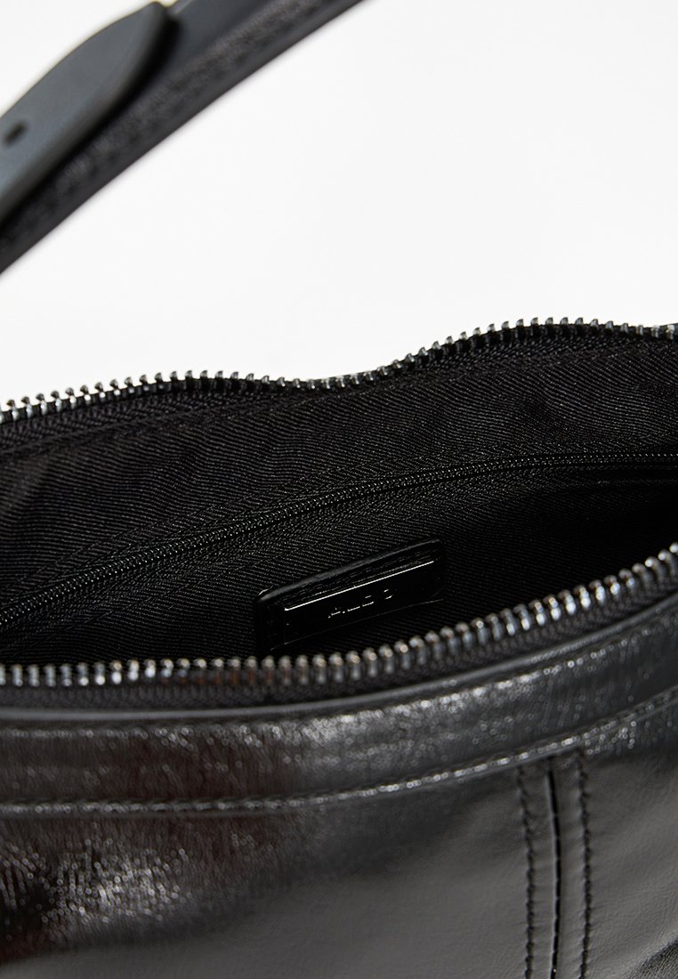 Futter einer schwarzen Ledertasche mit glatter Textur, ausgestattet mit einem Reißverschluss und einem kleinen Etikett, das sich gegen das dunkle Stofffutter abhebt.