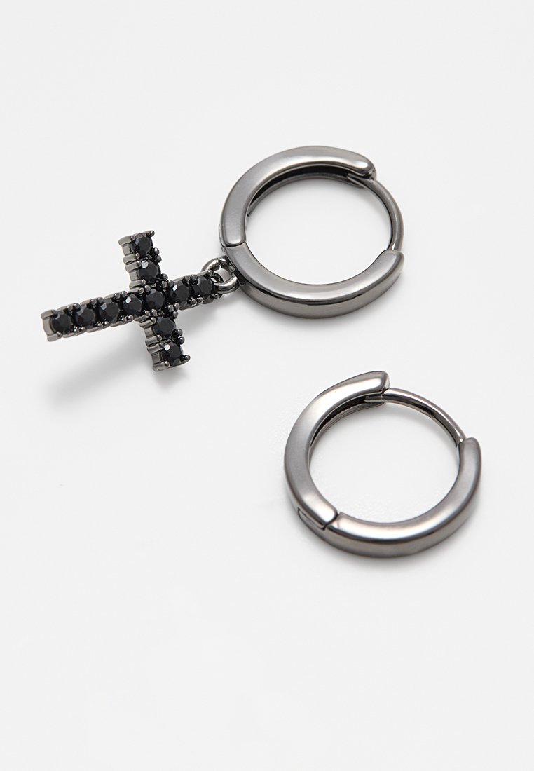 Orecchini ad anello in tono argento con pendente a croce. La croce presenta pietre nere. Finitura metallica liscia, forma circolare e chiusura sicura.