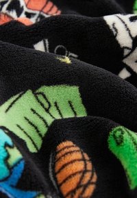 Tessuto di felpa nera con motivi di cartoni animati colorati, tra cui creature verdi e conchiglie arancioni, evidenziando una consistenza morbida e colori vivaci.
