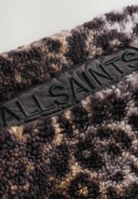 Faux-Fur-Stoff in Dunkelbraun und Beigetönen mit einer plüschigen Textur. Verfügt über ein schwarzes gesticktes Etikett mit der Aufschrift "ALLSAINTS."