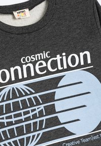 Grå bomulls sweatshirt med texten "cosmic connection" i vitt, samt en ljusblå grafisk bild av en jordglob och linjer, och ribbad krage.