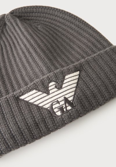 Bonnet en maille côtelée gris foncé avec un logo aigle brodé en blanc et noir et les lettres GA sur le revers.