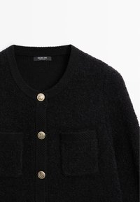 Cardigan lavorato a maglia nera con scollatura tonda, due tasche a toppa anteriori e tre bottoni decorativi dorati al centro.