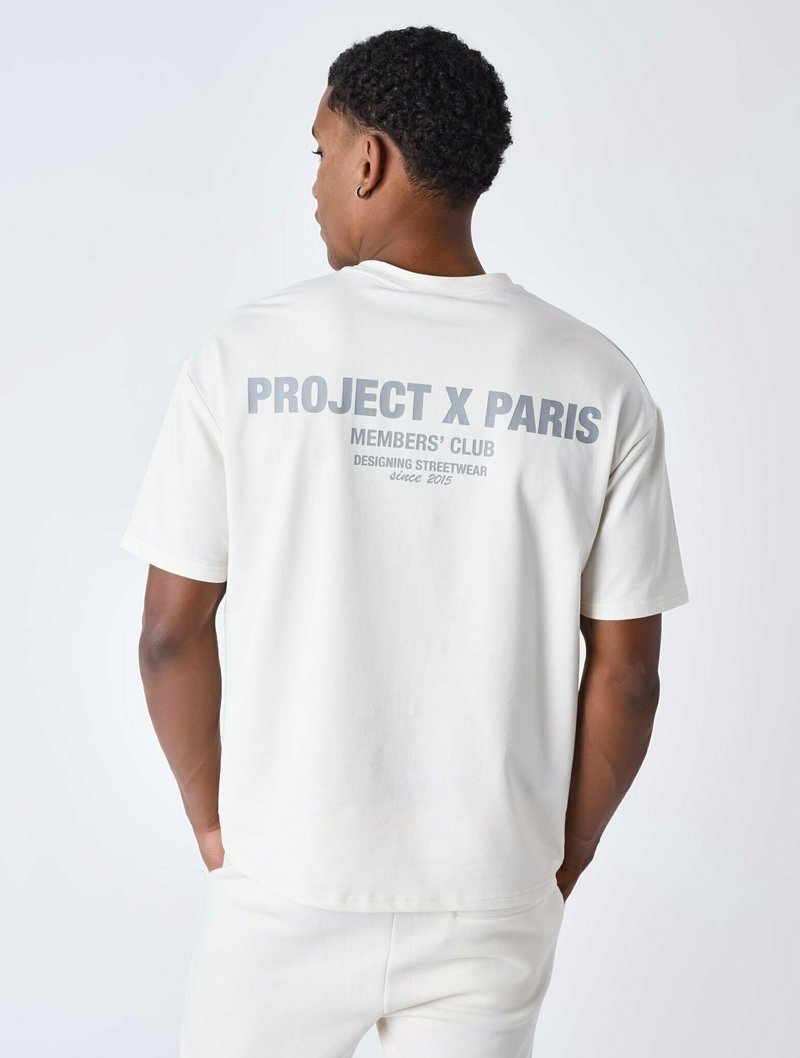 Witte t-shirt met een ronde halslijn en korte mouwen, met grote grijze tekst op de achterkant die zegt "PROJECT X PARIS MEMBERS' CLUB."