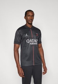 Fekete sportmez függőleges csíkokkal, piros díszítésekkel és kerek nyakkal. A "QATAR AIRWAY" feliratot és egy logót visel a bal mellrészen.