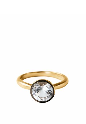 Anillo de oro con una única piedra preciosa redonda grande y clara montada en un engaste de tipo bisel sobre un fondo blanco.