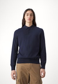 Ναυτικό μπλε μακρυμάνικο πουλόβερ πόλο με κλασικό γιακά, τρεις κουμπιά μπροστά και ριμπ μανσέτες και στρίφωμα. Υλικό από μίγμα βαμβακιού.