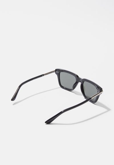 Occhiali da sole neri rettangolari con lenti grigie. Montatura in plastica spessa, con dettagli in metallo sull'arco. Stanghette nere sottili, texture liscia e lucida.