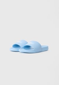Sandale slip-on de culoare albastru deschis, cu bretele late, având un logo alb de crocodil pe fiecare bretea, prezentate pe un fundal simplu.