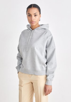 Grijze hoodie van zachte stof met een relaxte pasvorm, voorzien van een capuchon, koord en geribbelde manchetten en onderkant, gecombineerd met beige broeken.