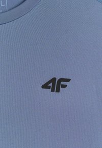 Gros plan d’un tissu bleu avec un logo noir « 4F » imprimé près du centre.