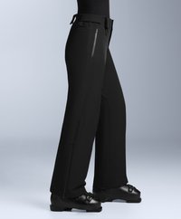 Černé voděodolné lyžařské kalhoty s uvolněným střihem, mají zipové kapsy a nastavitelné pas, v kombinaci s černými lyžařskými botami.