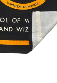 Tissu noir et orange avec un texte partiellement visible "ÉCOLE DE W... ET WIZ," coin relevé montrant le dessous gris et blanc.