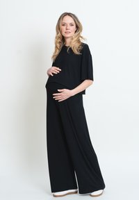 Completo maternità nero composto da una blusa morbida a maniche corte e pantaloni a gamba larga. Tessuto morbido, design minimal e vestibilità comoda.