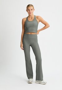 Crop top grigio a coste e pantaloni svasati in un morbido tessuto testurizzato. L'outfit presenta un design aderente con una palette di colori coordinata.