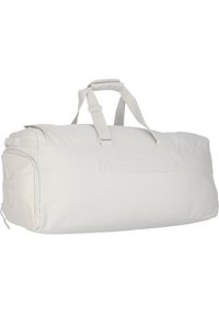 Bolso de deporte en tela gris claro con asas dobles y un bolsillo lateral. Presenta una textura suave y un diseño minimalista con un acento de logo.