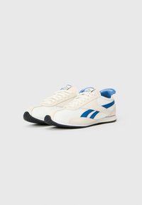 Adidași albi cu accente albastre, realizați din suede și plasă. Dispun de o talpă din cauciuc și un superior texturat cu vârful neted.