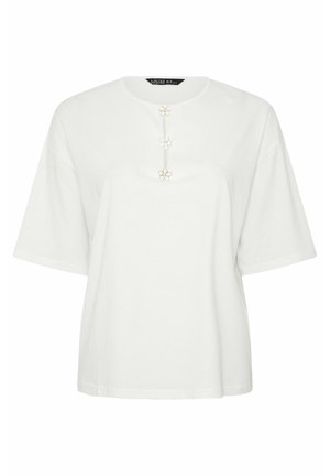 Valkoinen löysä lyhythihainen paita, jossa pyöreä pääntie ja keskellä etuosaa kolme koristeellista valkoista kukkanappia.