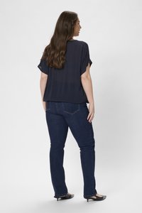 Námořnická modrá, krátký rukáv, top spárovaný s tmavě modrými džíny. Top je volného střihu; džíny mají slim fit s rovný slim střih. Černé boty na podpatku.