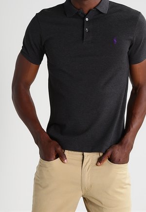 Mörkgrå pikétröja i bomull med klassisk krage, treknappslå och en liten lila logotyp på bröstet.