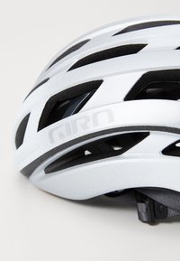 Weißer Fahrradhelm mit schwarzem Innenschaum, hergestellt aus leichten Materialien. Verfügt über ein aerodynamisches Design und einen verstellbaren Riemen für eine optimale Passform.