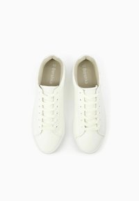 Vita snörskor i spetsig syntetisk material med en slät design, rund tå och minimalistisk logotyp på innersulan.