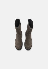 Brown, suede ankle boots with a rounded toe, side zip closure, and rubber sole. Textured upper and elasticized panels for flexibility.