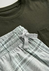 Dunkelgrünes T-Shirt mit kurzen Ärmeln und Brusttasche, kombiniert mit grauen karierten Shorts mit Kordelzug und elastischem Bund.