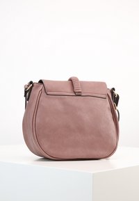 Okrągła, miękka torebka ze skóry w kolorze jasnoróżowym z klapką, z teksturowanym akcentem, złotymi detalami i odczepianym paskiem.