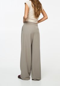 Brede broekspijpen in lichtgrijze stof, met een gladde textuur, hoge taille, zijzakken en een subtiel detail van een achterzak.