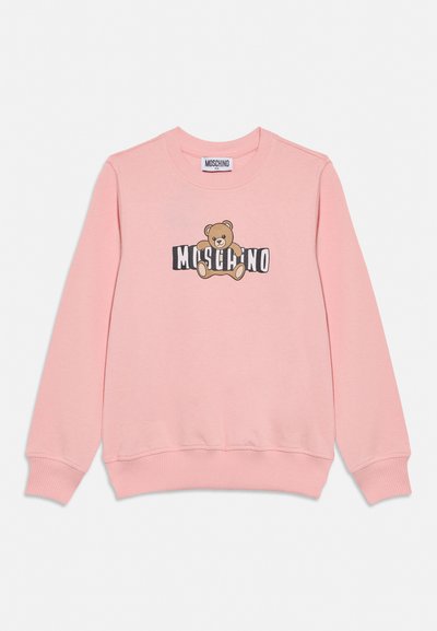 Rožinės spalvos ilgarankovė džemperis su siūlėmis rankogaliuose ir apačioje, ant priekinės dalies yra meškiuko atvaizdas ir užrašas „Moschino“.