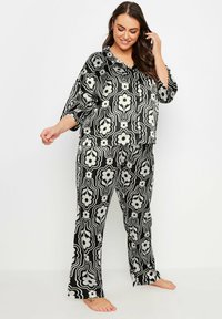 Svart och vit blommönstrad pyjamasset som har en löst sittande topp med krage och matchande byxor med raka ben. Mjuk tygkvalitet.