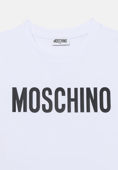 Λευκό μπλουζάκι κοντό μανίκι με στρογγυλή λαιμόκοψη και μεγάλο μαύρο γράψιμο "MOSCHINO" μπροστά, καθώς και ετικέτα "MOSCHINO KID" στη λαιμόκοψη.