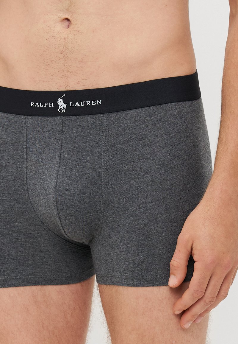Heren grijze katoenen boxershorts met een zwarte elastische tailleband, met het "RALPH LAUREN" logo in het wit. Glad oppervlak, getailleerd ontwerp.