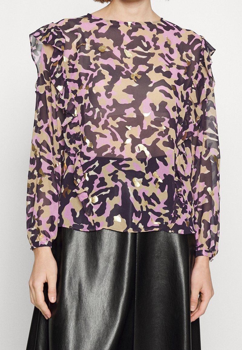 Durchsichtige lila Camouflagemuster-Bluse mit Rüschendetails, die Schattierungen von Pink, Braun und goldenen Metallic-Elementen enthält. Lange Ärmel, runder Ausschnitt.