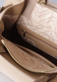 Borsa a mano in pelle beige aperta per mostrare la fodera in tessuto con marchio, tasca interna con zip e chiusura con zip dorata.