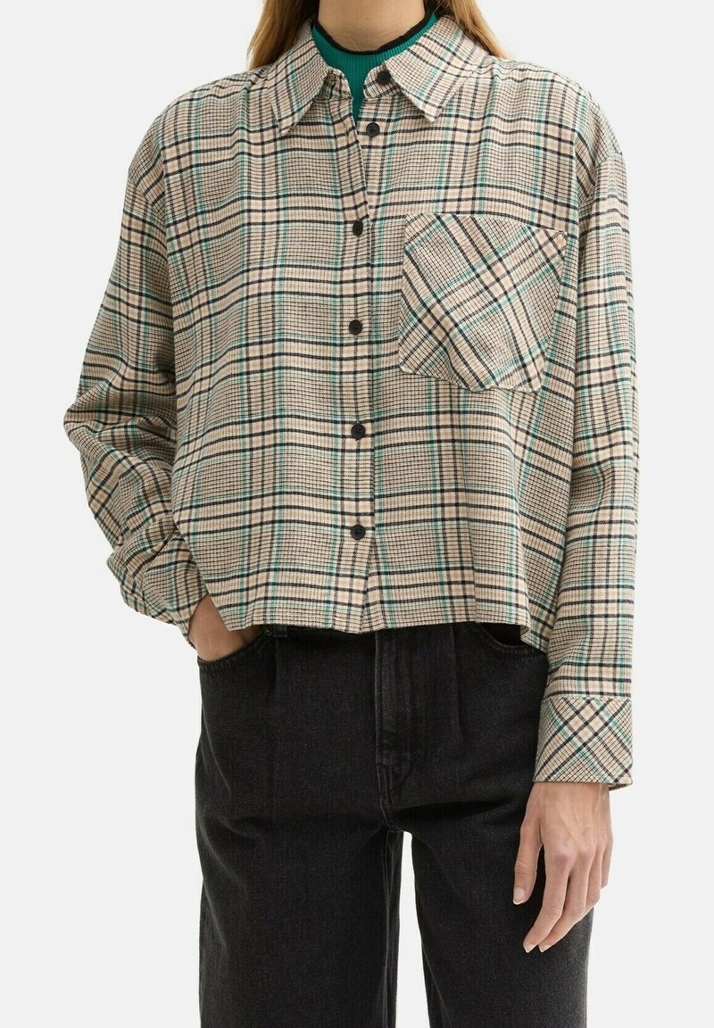 Cropped plaid shirt in beige with black and teal lines. Features a button-up front, long sleeves, and a single chest pocket.