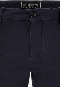 Pantaloni blu navy con zip frontale, chiusura a bottone e tasche laterali. Realizzati in tessuto liscio con una vestibilità aderente e dettagli minimi.