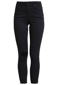 Jean skinny noir taille haute avec des déchirures usées sur la cuisse et le genou, doté d'un style à cinq poches et d'une fermeture par bouton.