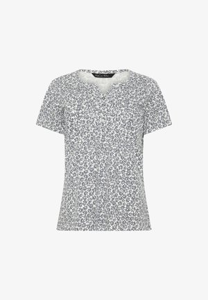 Blouse blanche à manches courtes avec motif floral noir, encolure ronde avec patte de boutonnage, et silhouette légèrement ajustée.