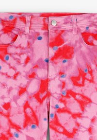 Roze denim broek met een tie-dye patroon met rode en blauwe spetters, vijf zakken en een voorste knoopsluiting.