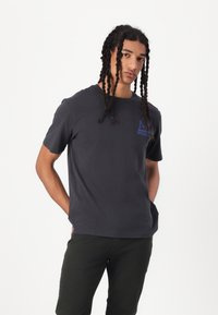 Gray cotton t-shirt featuring a blue logo on the left chest area. Short sleeves and a classic crew neck design.