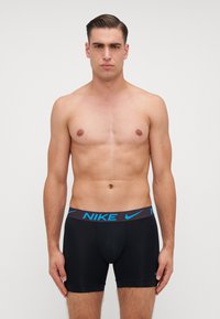 Nike férfi fekete boxer alsóneműk kék logós derékpánttal, szoros szabással, rövid lábakkal és sima anyagtextúrával.