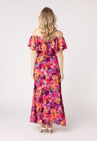Abito maxi con volant sulle spalle, motivo floreale vivace in rosa, arancione e viola. Tessuto fluido, lunghezza alla caviglia con vita aderente.