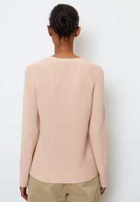 Pull tricoté rose clair avec un col rond, des manches longues et un motif texturé ; doté d'un ourlet légèrement incurvé et de coutures raglan.