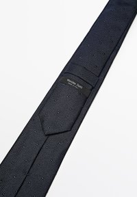 Marineblå slips lavet af struktureret stof med små prikkede mønstre. Har et syet label med teksten "Massimo Dutti Made in Italy."