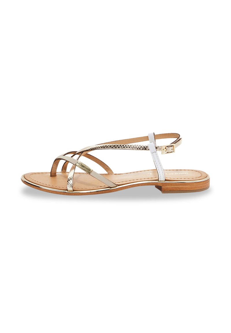 Sandalia plana con tiras metálicas doradas y blancas, diseño de punta abierta y suela de madera marrón claro. Incluye una correa ajustable en el tobillo.