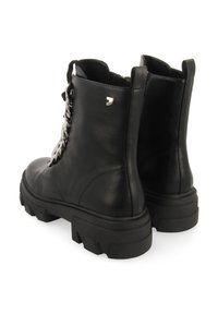 Botas negras de cuero hasta el tobillo con una suela negra gruesa, cordones en la parte delantera y un pequeño logotipo metálico en la parte trasera. Textura suave con un detalle mínimo.